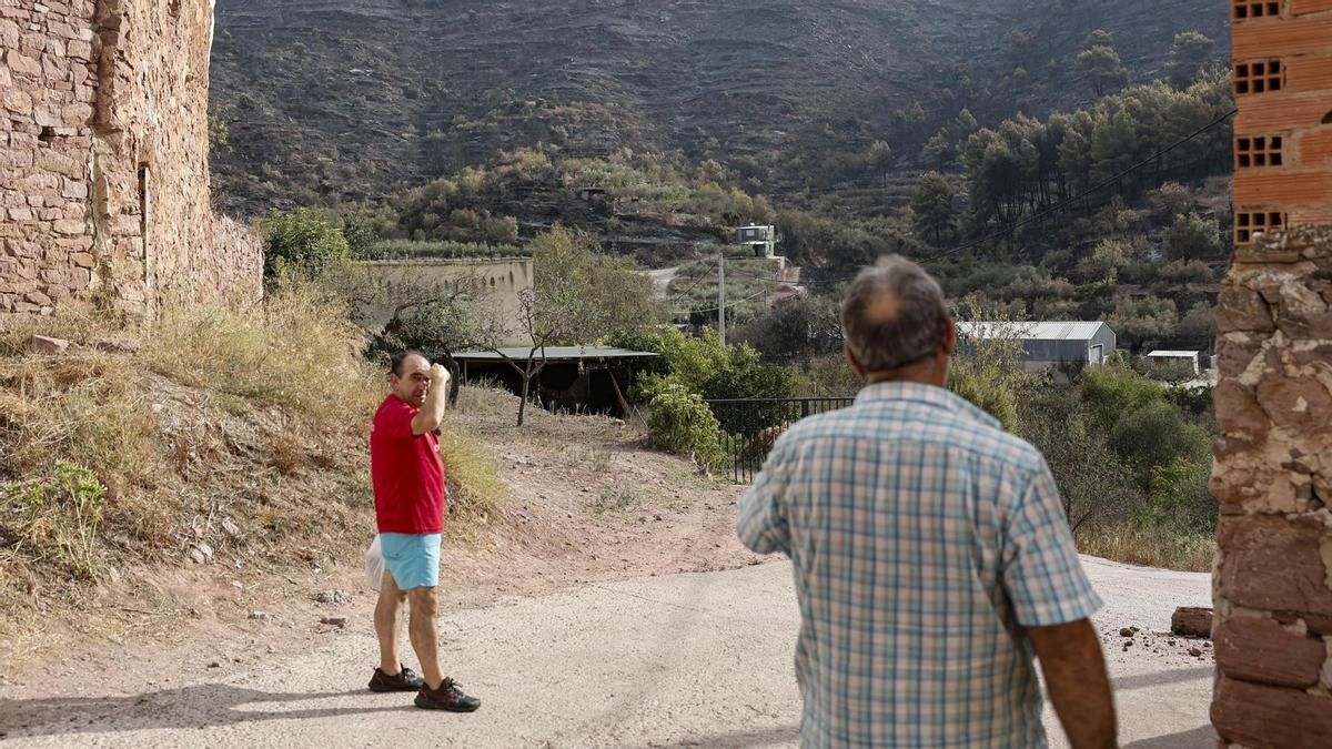 Dos vecinos de Gátova (Valencia) comentan la situación del pueblo tras el incendio de Segorbe (Castellón) que obligó a desalojar su su municipio. EFE/ Manuel Bruque