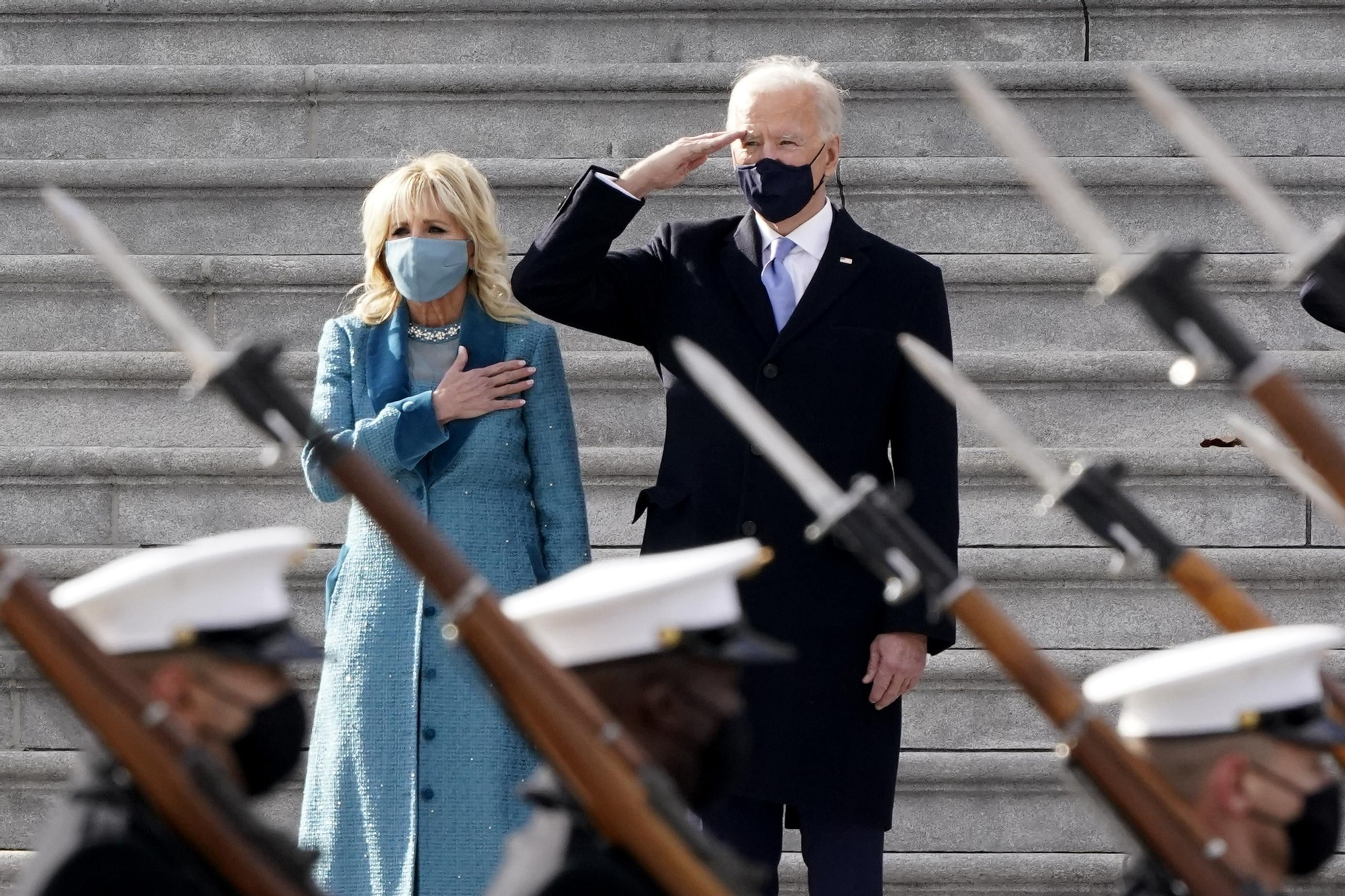 El presidente Biden y la primera dama saludan a una comitiva militar a la salida del juramento de cargo en el Capitolio