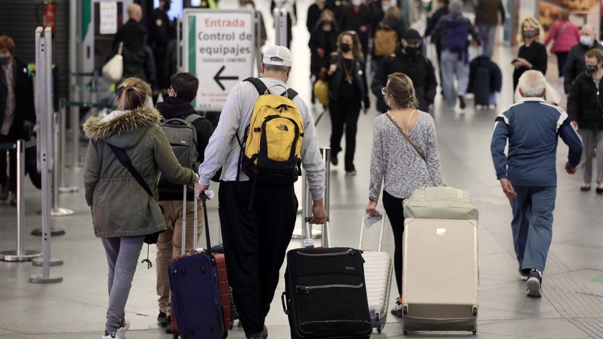 Varias personas, con maletas, se dirigen al control de equipajes en el día en que arranca la operación salida de Semana Santa 2022.