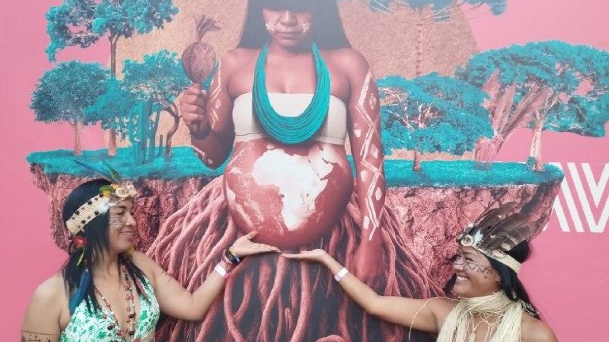Dos mujeres indígenas venezolanas de la etnia Pemón posan junto a uno de los murales pintados en Belém con motivo de la COP30.