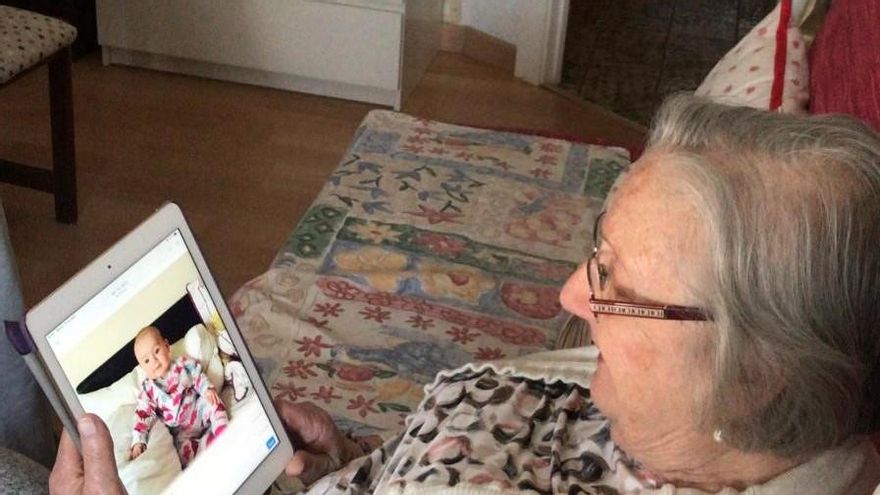 Balbina mirando en la Tablet fotos de una de sus biznietas