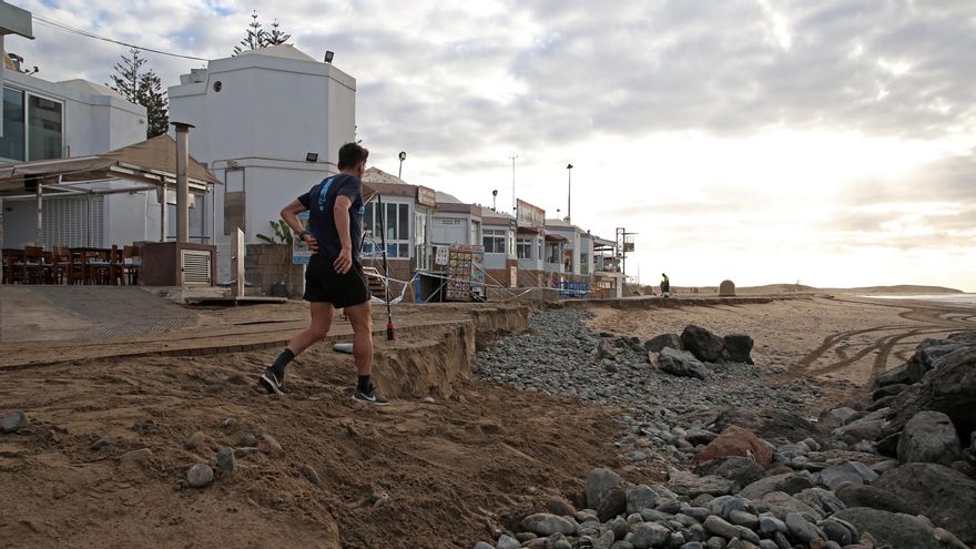 Una persona desciende a la arena de la playa de Maspalomas tras la retirada de una parte de la pasarela de madera en un tramo afectado por la pleamar.