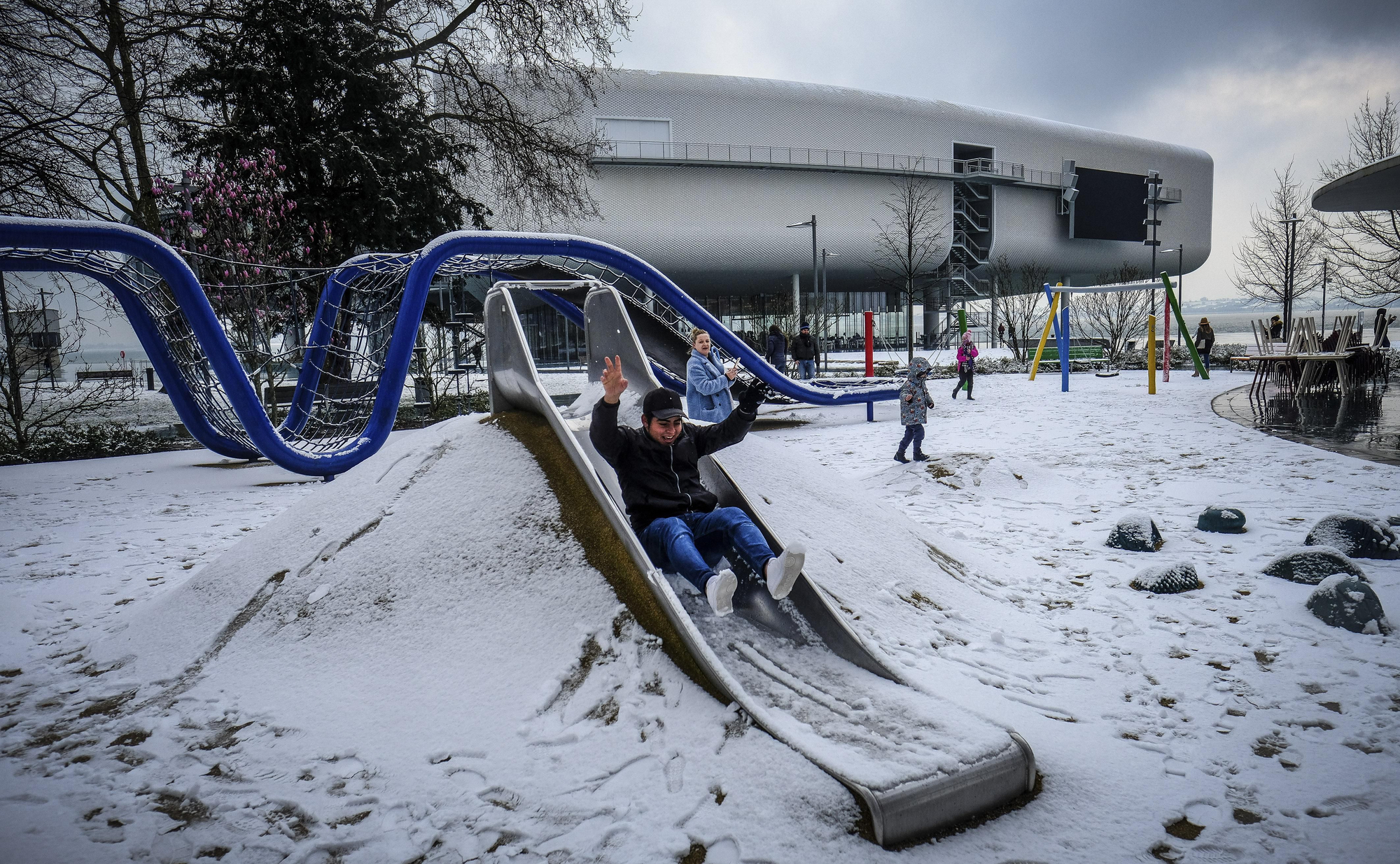 Un chico se tira por un tobogán delante del Centro Botín en los Jardines de Pereda durante una inusual nevada en Santander. | NACHO CUBERO