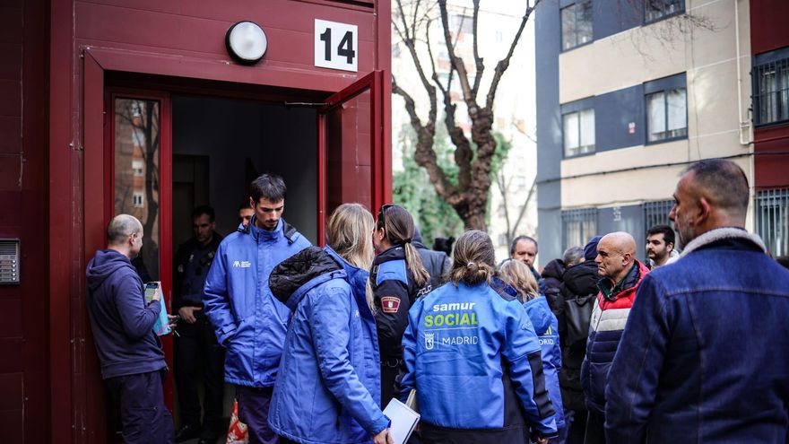 Miembros de Samur Social y, al fondo, agentes de la Policía en la puerta del edificio donde han desahuciado a una familia en Villaverde