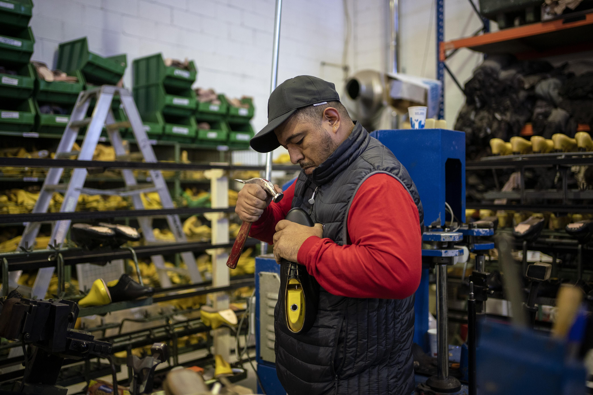 Un trabajado ensambla a mano las piezas de un zapato en Peris