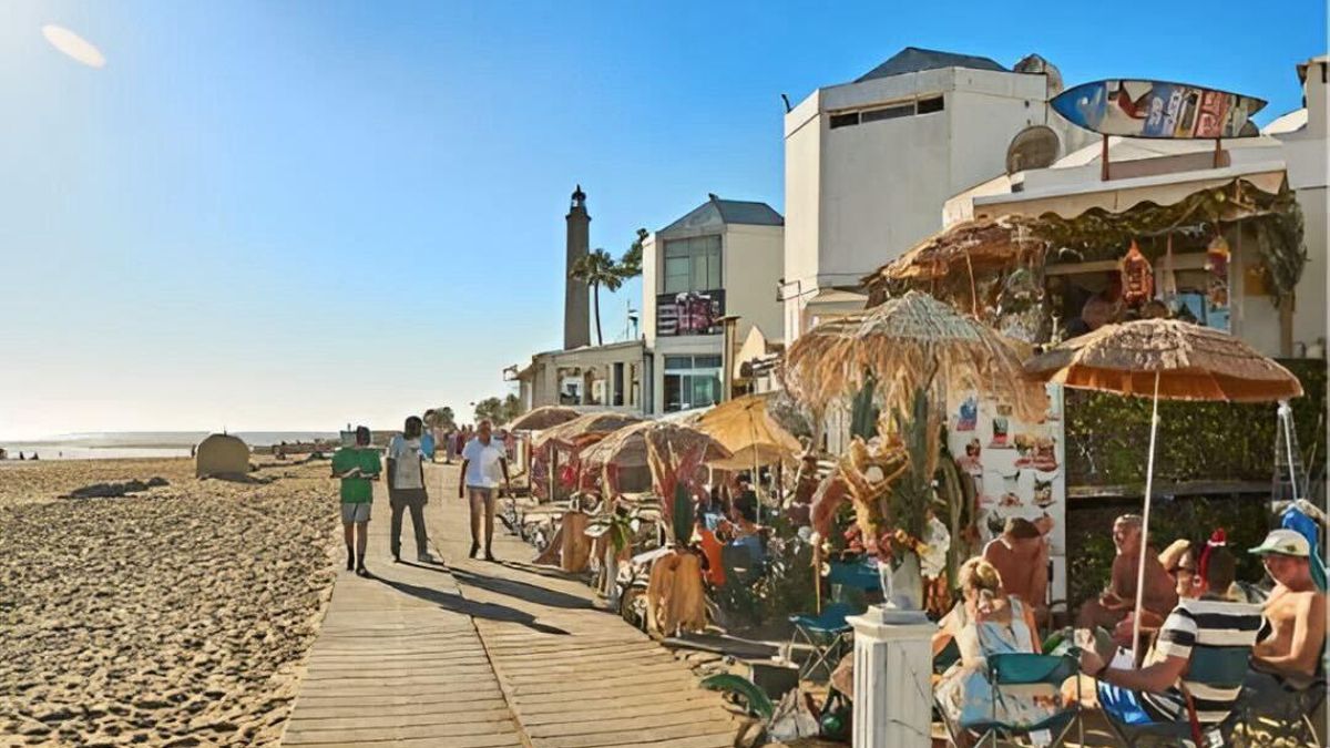 Paseo en Maspalomas, ocupado por sillas y mesas de locales de hostelería.