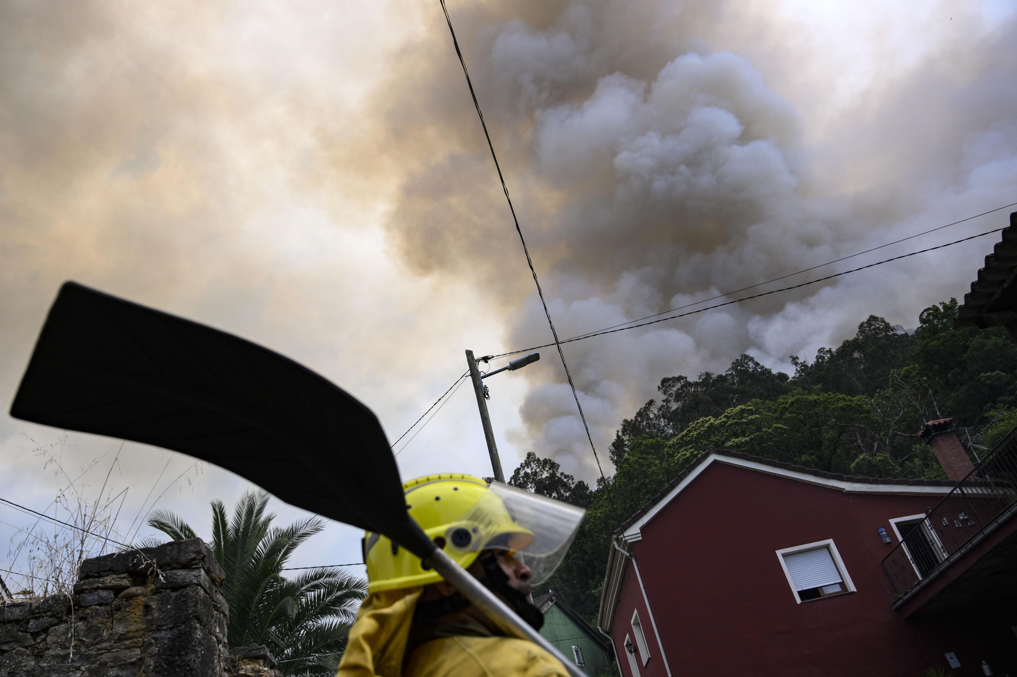 Un miembro del servicio de Bomberos, durante las labores de extinción del incendio en Peñaflor, en el concejo asturiano de Grado.