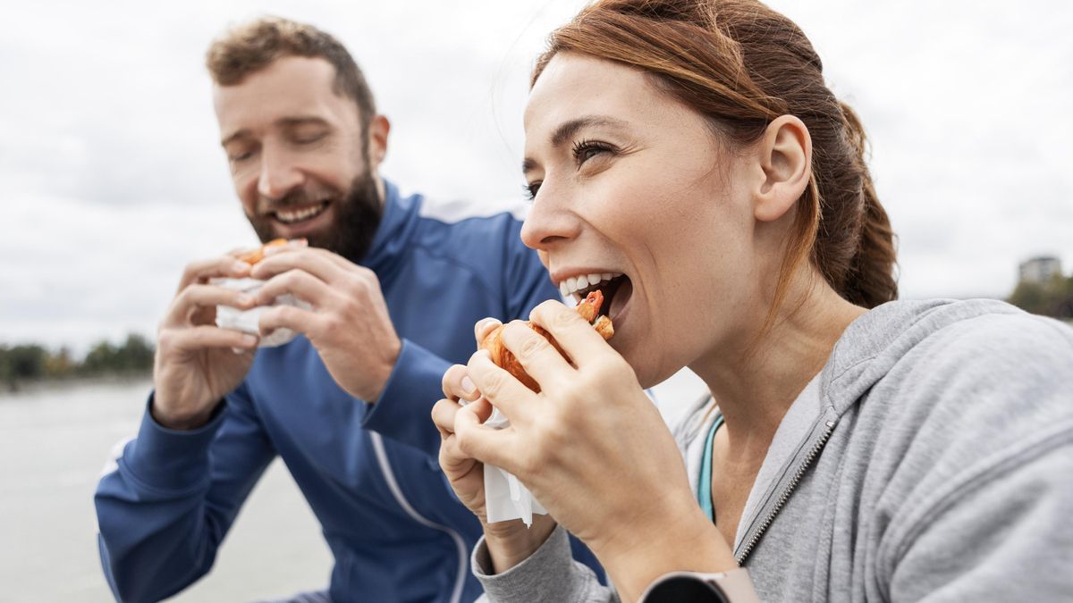 Dos excursionistas comen bocadillos durante una ruta