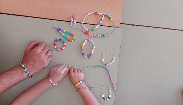 Niños y niñas de la asociación 'Entre Todos' realizan pulseras con abalorios