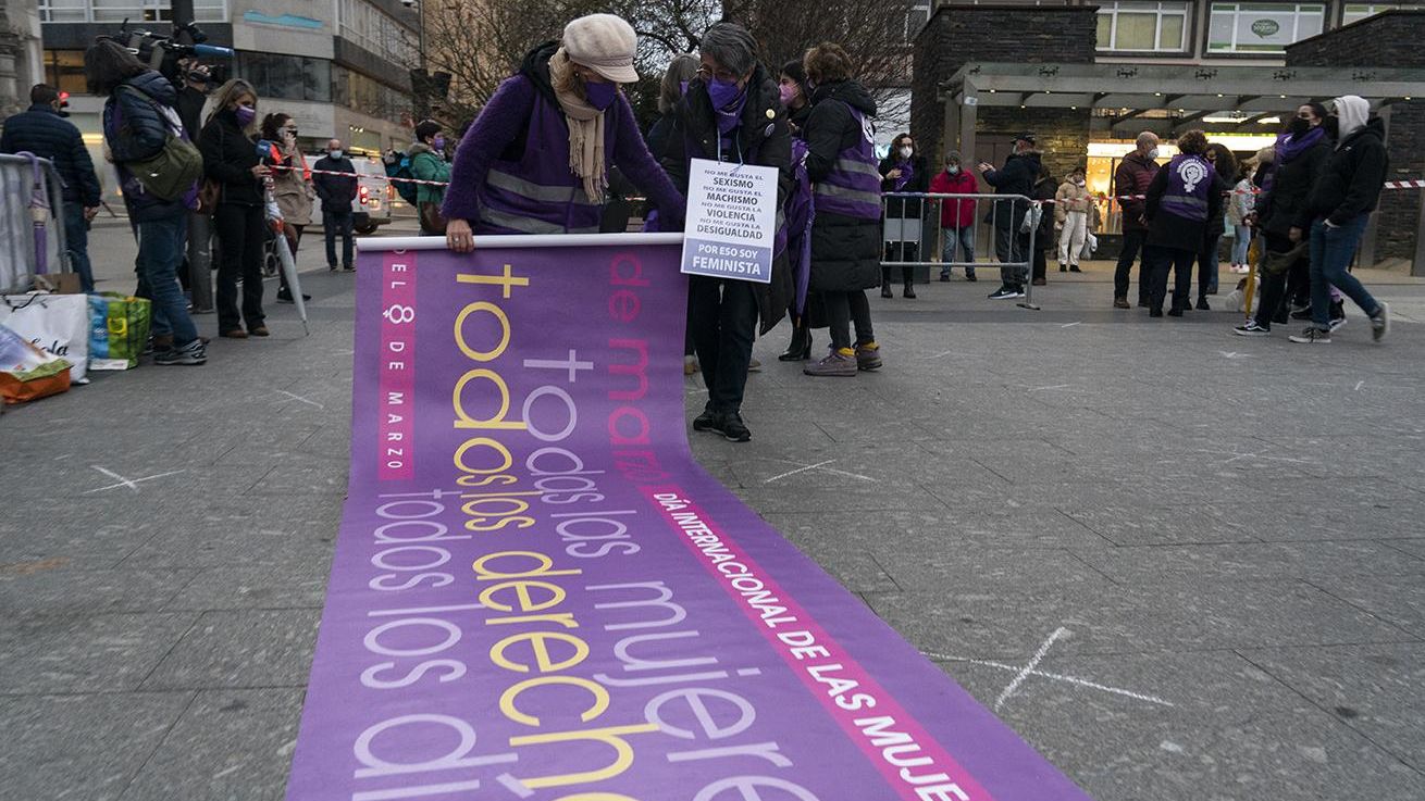 Un mujer enrolla la pancarta de la concentración feminista por el 8M en Santander.