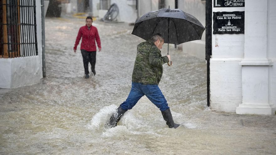 Vecinos de Grazalema (Cádiz) caminan por una calle inundada debido a las intensas lluvias que se registran este miércoles en la localidad gaditana.
