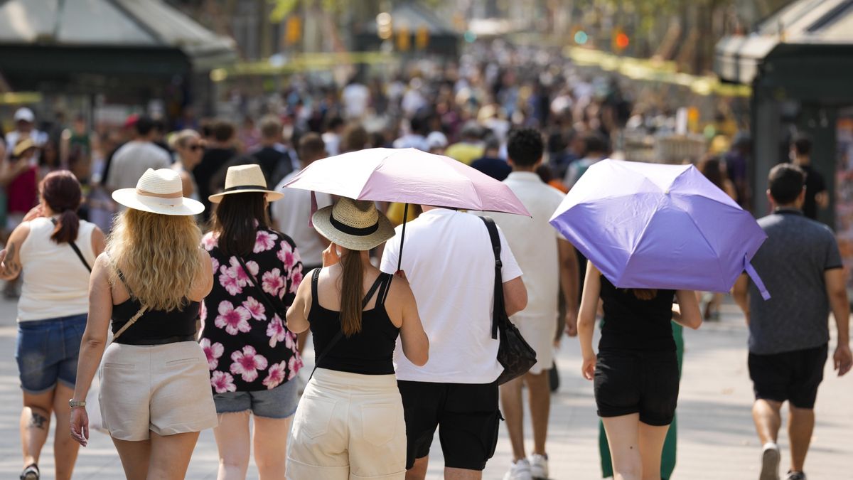 Personas protegiéndose del calor mientras pasean por Barcelona, en una foto de archivo