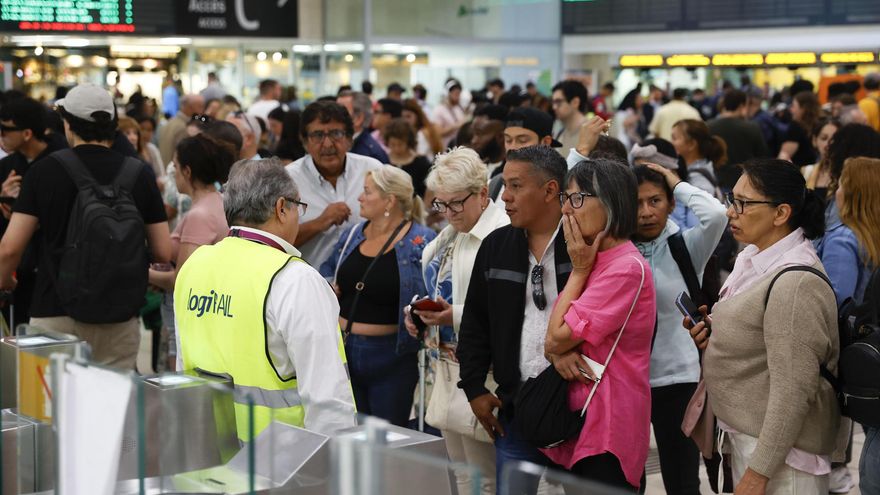 Decenas de viajeros esperan en la estación de Sans en Barcelona este domingo.