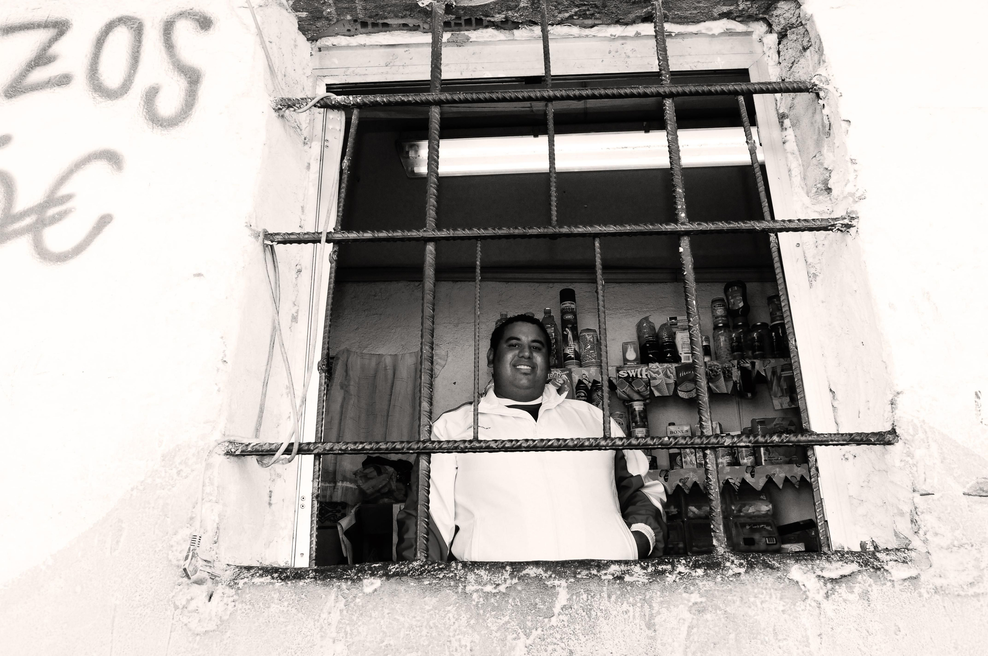Faisal Benani tras la reja de su pequeña tienda de alimentación
