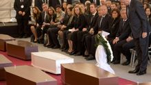 El comisario europeo de Inmigración Dimitris Avramopoulos, frente a los cuerpos de los fallecidos en el naufragio de 800 personas en su intento de llegar a Europa. / Hoy las autoridades europeas deciden un plan de medidas con el supuesto objetivo de frenar las muertes en el Mediterráneo. / Imagen: AP / Alessandra Tarantino