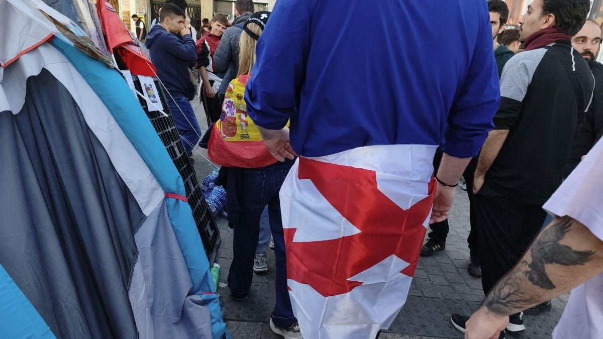 Un hombre con una bandera carlista, con la cruz de Borgoña
