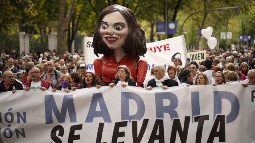 Varias personas sujetan una pancarta con el lema de "Madrid se levanta" en el Paseo del Prado.