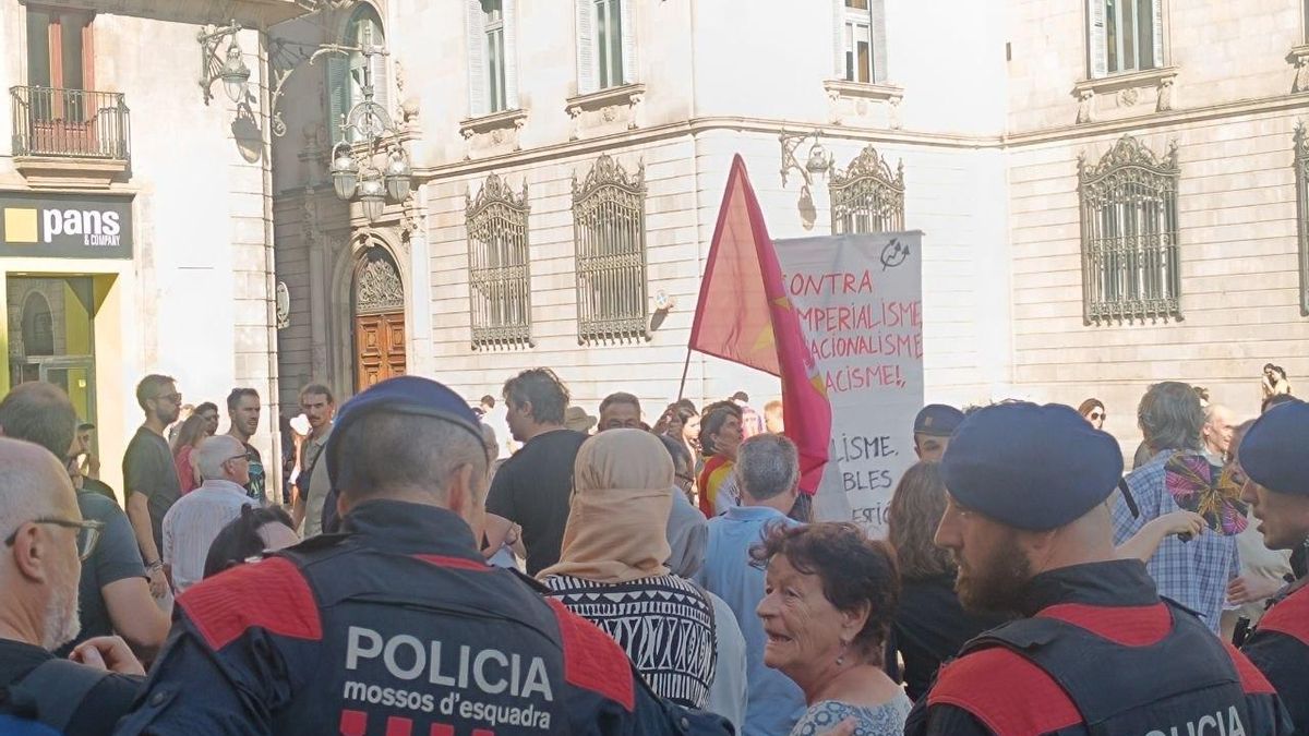 Agentes de los Mossos impiden el acceso de los vecinos a parte de la plaza para protestar por la manifestación xenófoba de Barcelona.