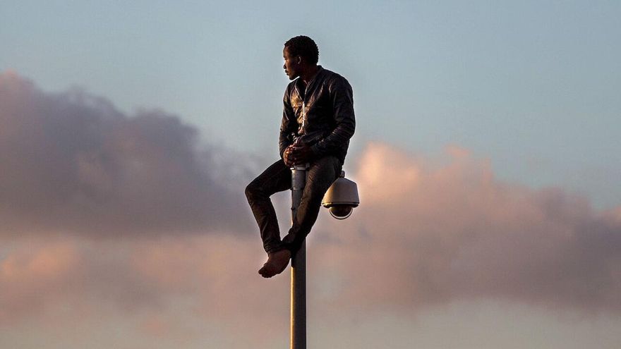 Un persona migrante durante un salto a la valla de Melilla.