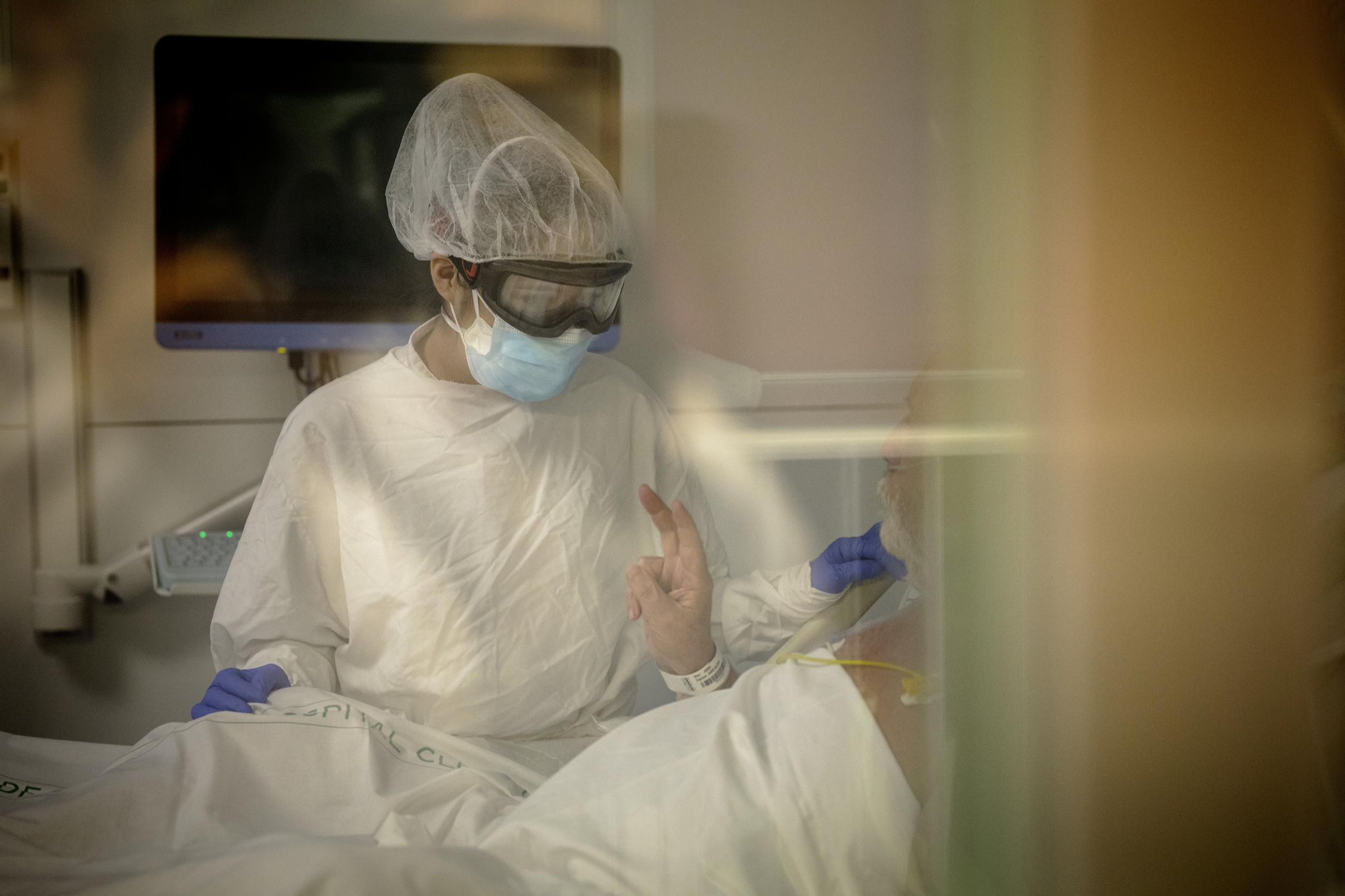 Un paciente de COVID hace el signo de victoria con los dedos ante la auxiliar de enfermería que lo atiende. En España, 7 de cada 10 pacientes COVID que ingresan en la UCI sobreviven.