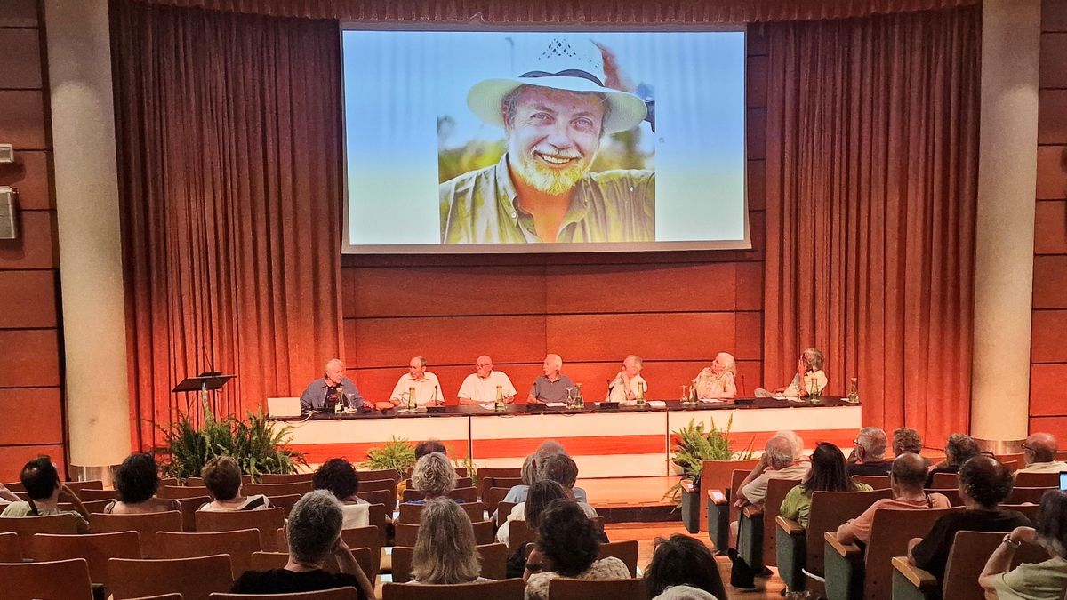 Participants en la trobada sobre els 50 anys de l'ecologisme al País Valencià amb una fotografia de Josep Vicent Marqués a la pantalla.