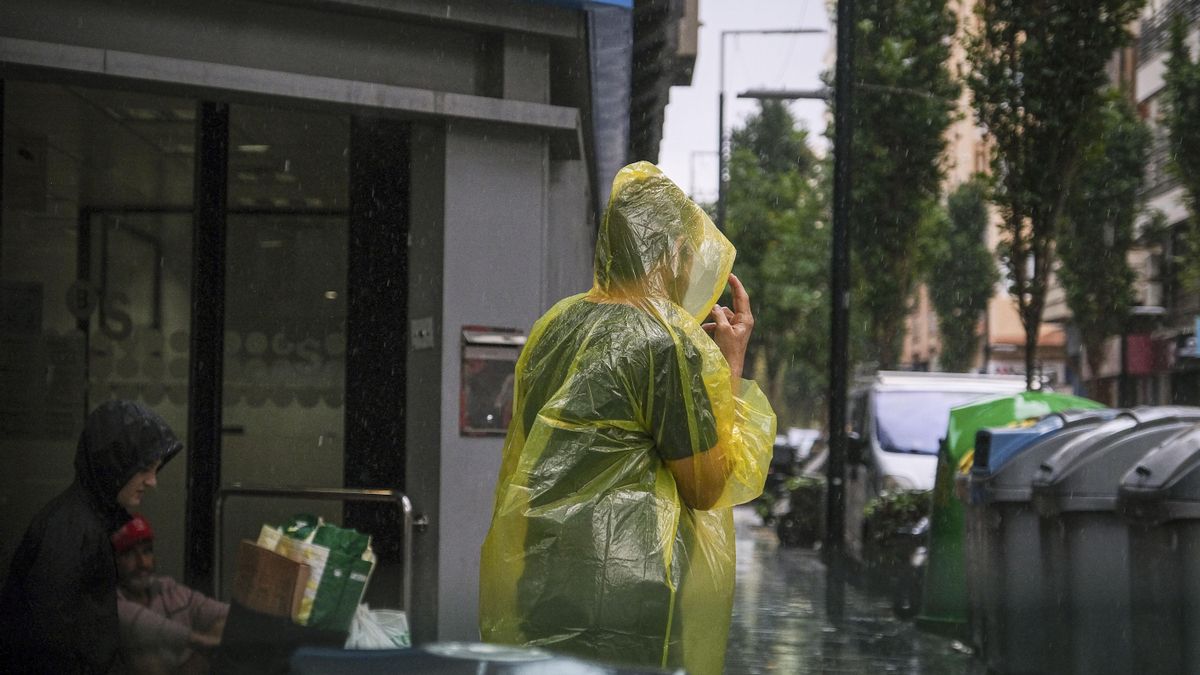 Una persona se protege de la intensa lluvia en Alicante