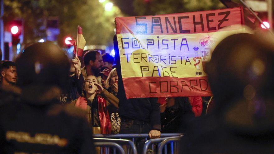 Detalle de una pancarta sobre una bandera de España durante la concentración convocada contra la ley de amnistía frente a la sede del PSOE de la calle Ferraz, este domingo.