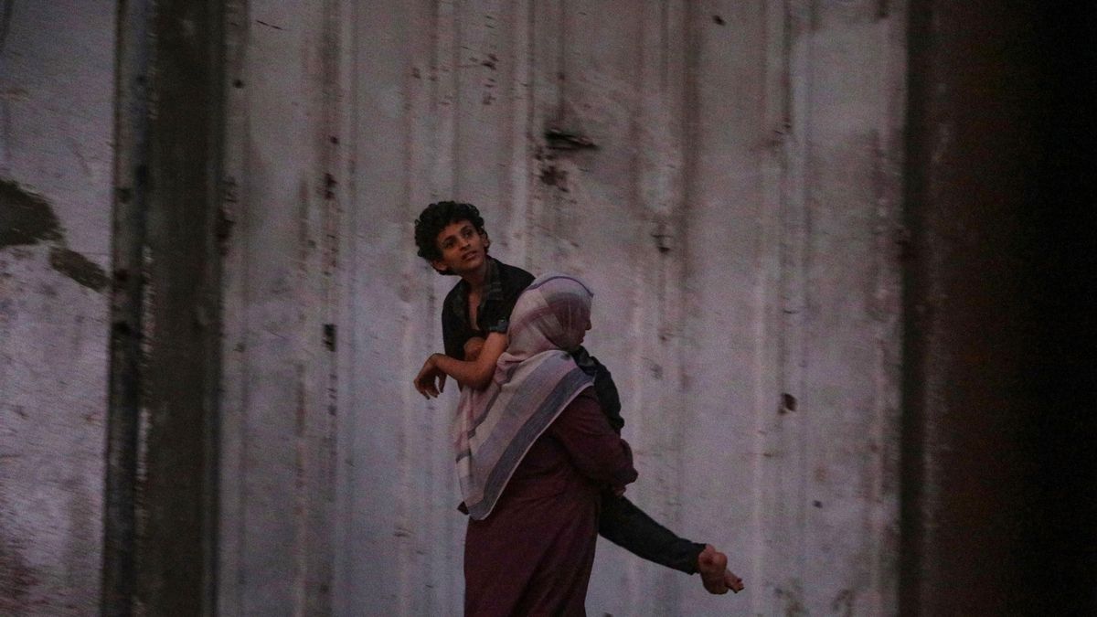 Una madre palestina huye de ciudad de Gaza cargando a su hijo enfermo el 28 de septiembre de 2025.