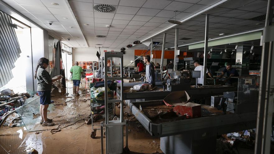 Varias personas tratan de recuperar alimentos de una tienda de Aldaia destruida por la riada.