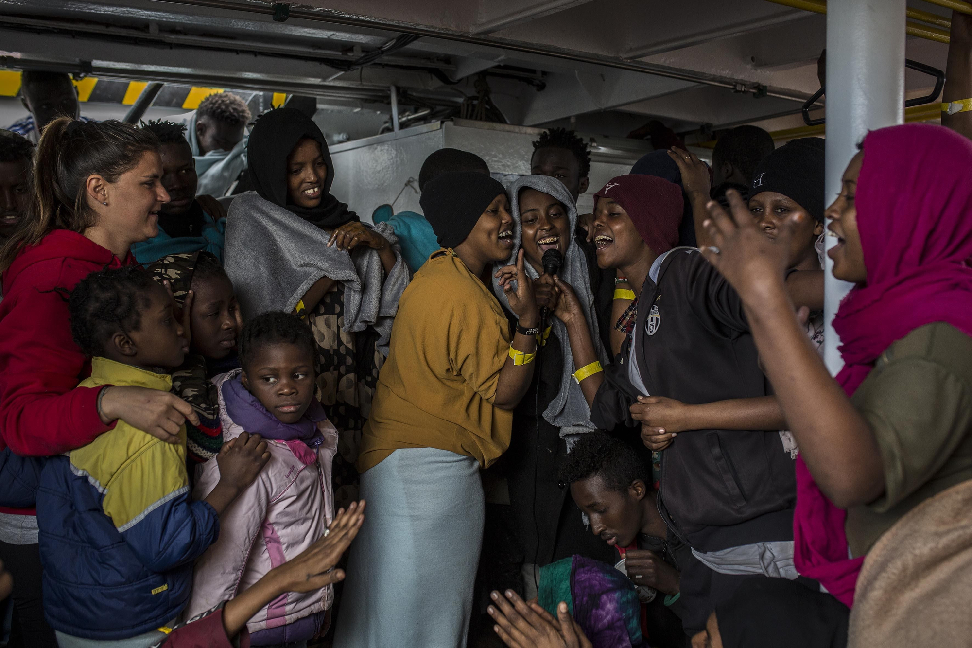 Un grupo de mujeres cantando con un altavoz instalado por los voluntarios de Proactiva Open Arms en la cubierta del barco. Decenas de mujeres, niños y hombres se animaron a participar en la actividad / Olmo Calvo