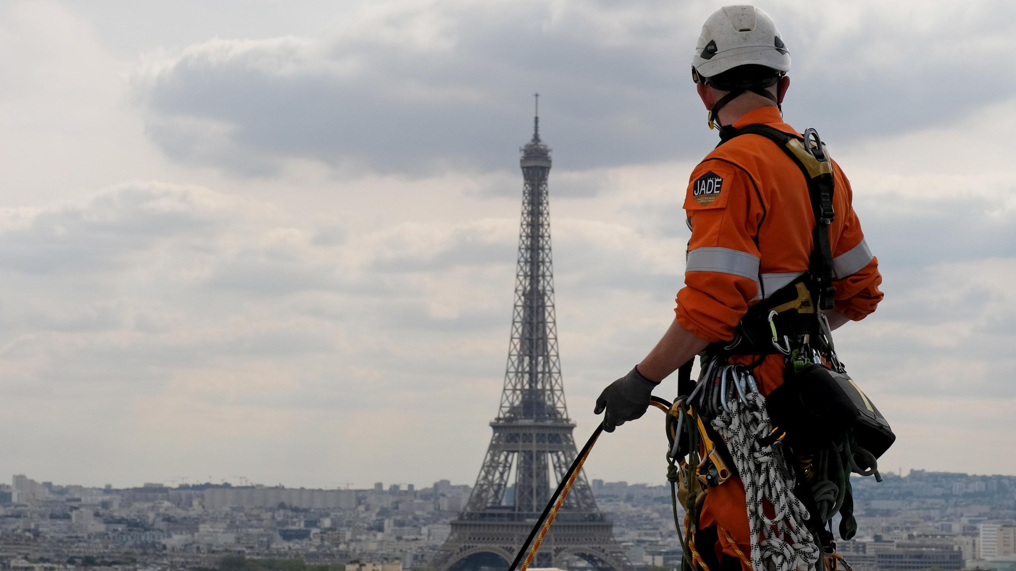Un operario en lo alto del Arco del Triunfo, observa la Torre Eiffel