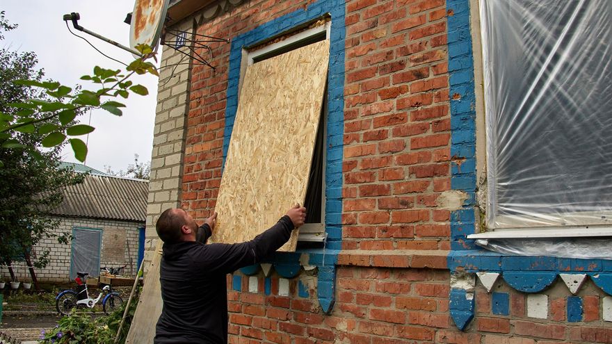 Un hombre cubre la ventana de un edificio dañado por los bombardeos rusos en la ciudad de Korobochkyne, en la región de Járkov.