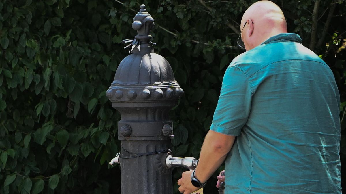 Un hombre bebe agua en una fuente en una jornada de calor.-ARCHIVO