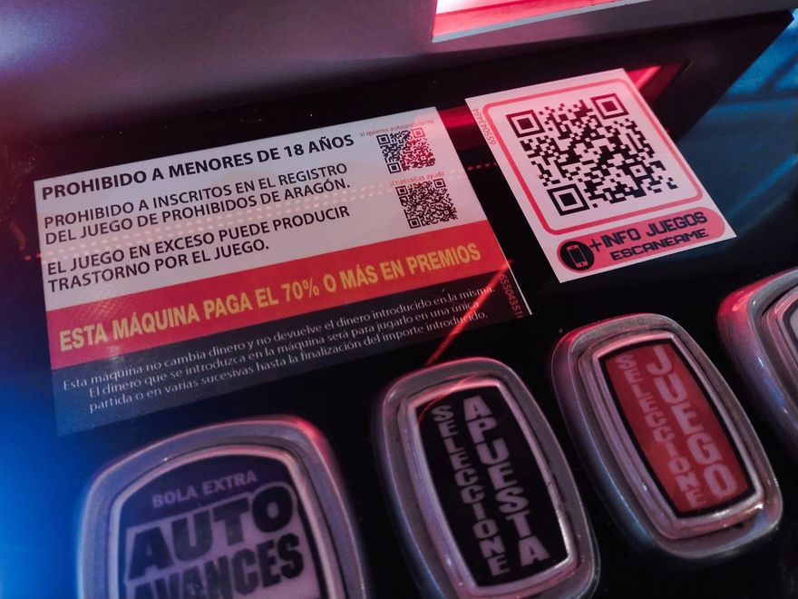 Mensajes de advertencia en una máquina recreativa situados junto a un QR que enlaza con las ofertas de juego de la empresa.