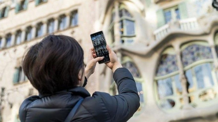 Una turista realiza una fotografía con su teléfono móvil a la Casa Batlló de Barcelona