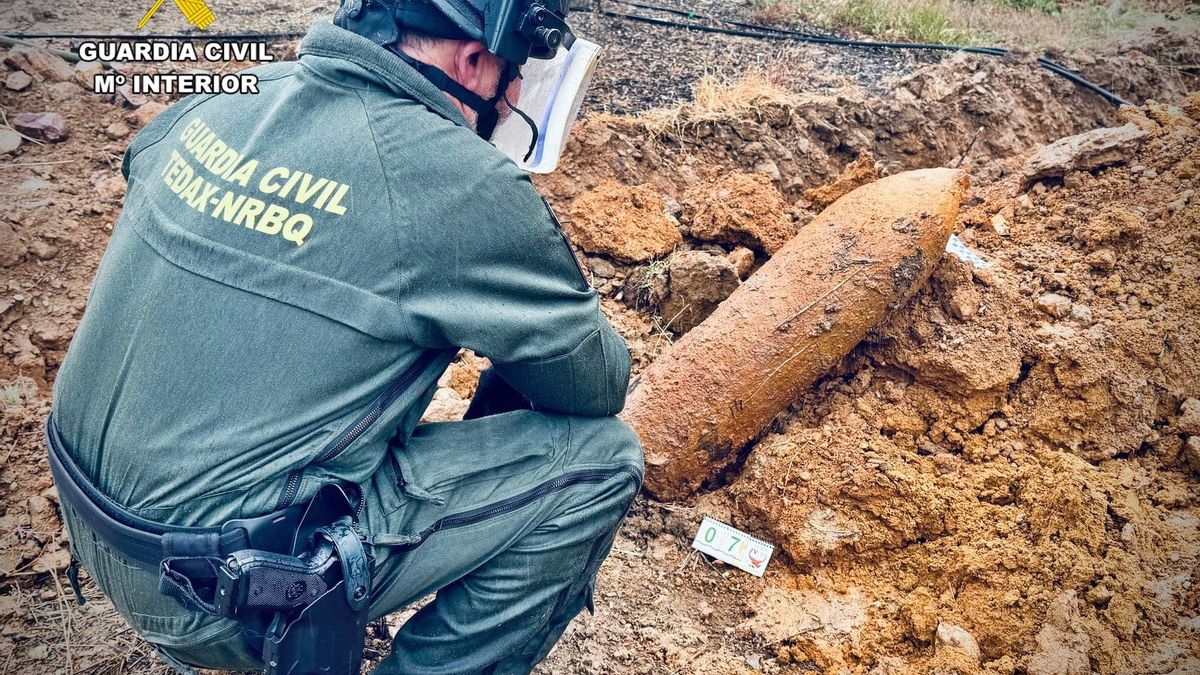 Un agente de la Guardia Civil y la bomba de aviación de la guerra encontrada en un olivar de Villanueva de la Serena, Badajoz