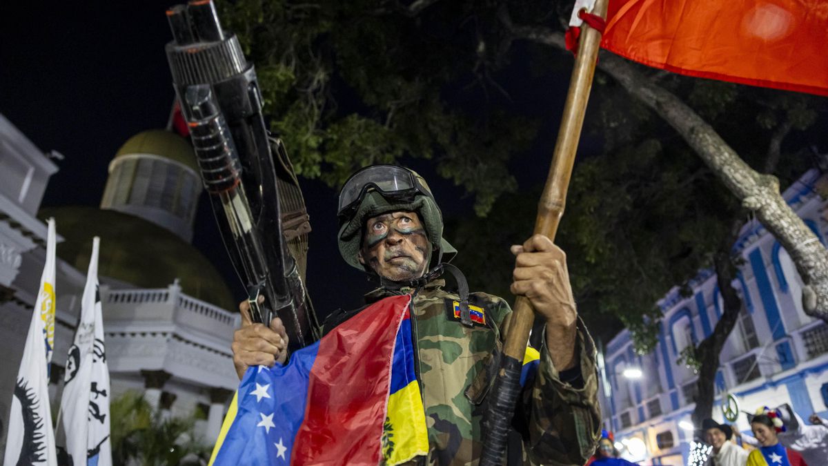 Un hombre sostiene un arma y una bandera durante una manifestación por el 26 aniversario de la Constitución de Venezuela en Caracas.