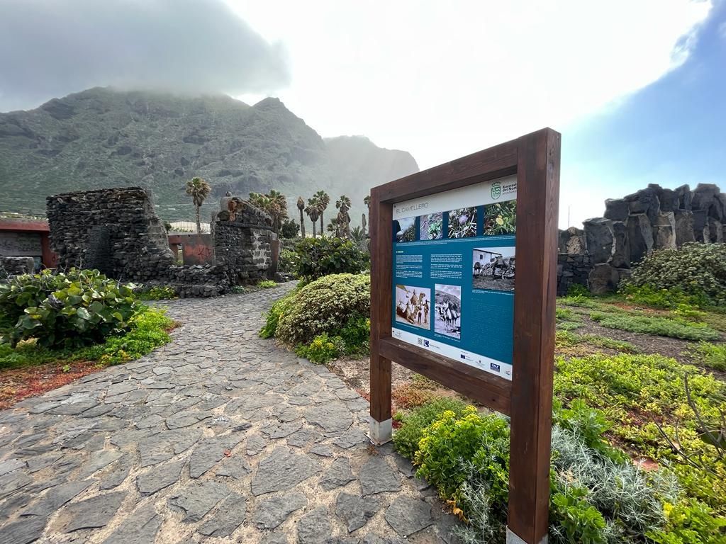 Un cartel recuerda por qué a este lugar se le conoce como El Camellero. A la izquierda, restos del antiguo establo de  los camellos. Al fondo, cara norte del macizo de Teno