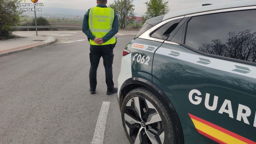 Agente de la Guardia Civil junto a su coche patrulla