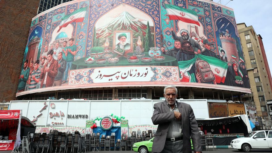 Ciudadanos iraníes pasan junto a una enorme valla publicitaria en la plaza Valise de Teherán.