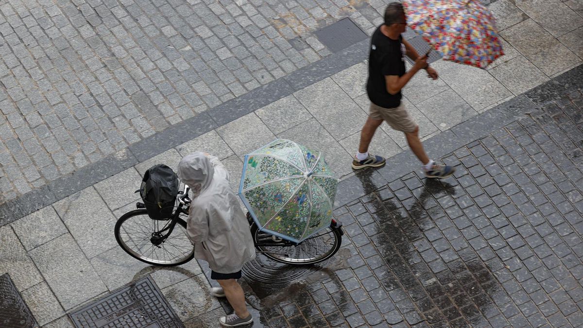 Dos personas caminan bajo una intensa lluvia.