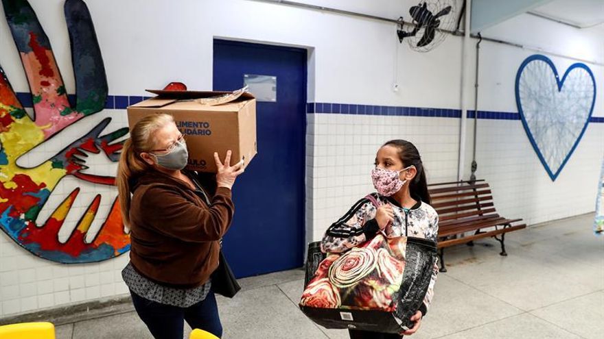 La empleada doméstica Cícera Claudino dos Santos, de 59 años, acompañada de su hija Ana Carolina dos Santos, de 10 años, recibe una cesta básica de alimentos el pasado 4 de junio, en la Escuela Municipal de Educación Bilingüe para Sordos (EMEBS) Mario Pereire Bicudo, distribuida por la Alcaldía de la mayor ciudad de América (12 millones de habitantes) en Sao Paulo (Brasil).