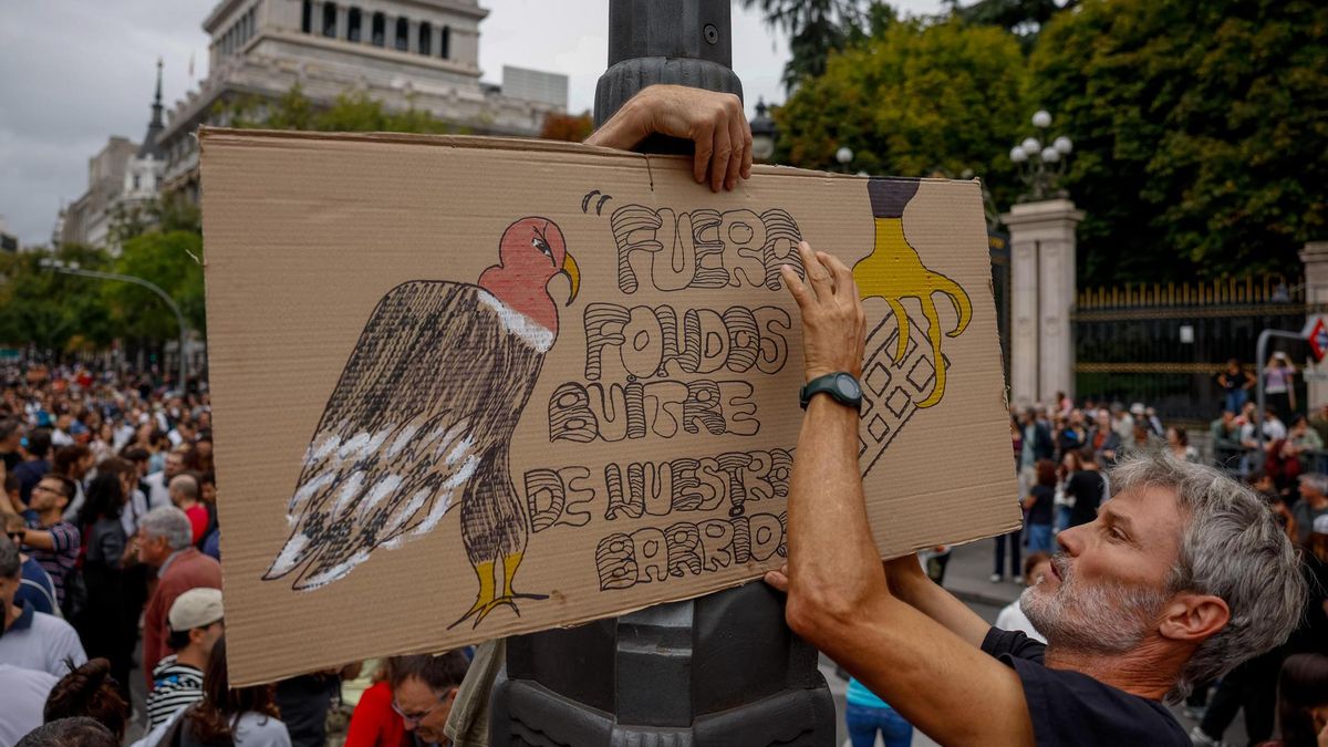 Una persona coloca un cartel en la manifestación contra la especulación de Madrid.