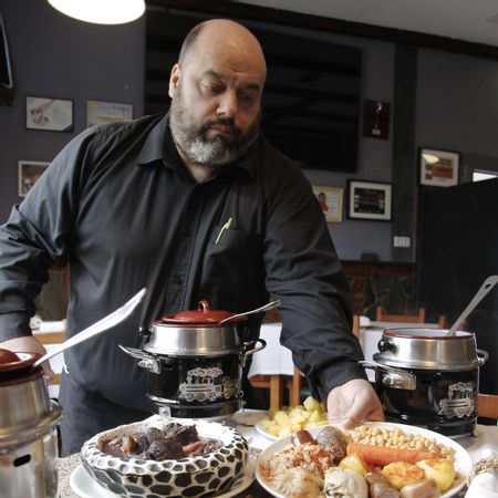Un camarero sirve un plato de cocido maragato en el restaurante avilesino.