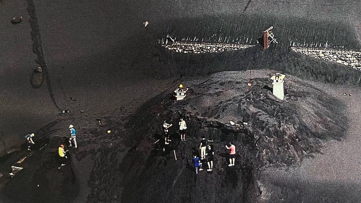 Operarios caminan sobre una casa sepultada por el volcán de La Palma / FOTO: Aldara Diéguez