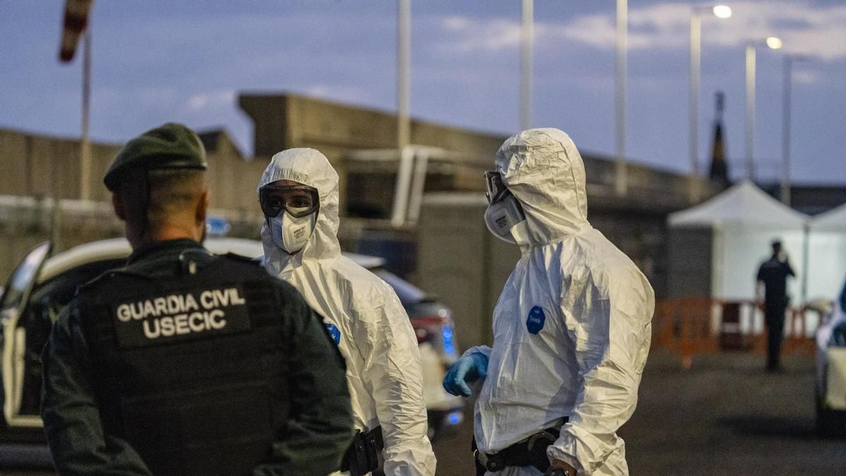 Personas con mono EPI esperan en el puerto mientras el crucero MV Hondius fondea cerca del puerto de Granadilla, a 10 de mayo de 2026