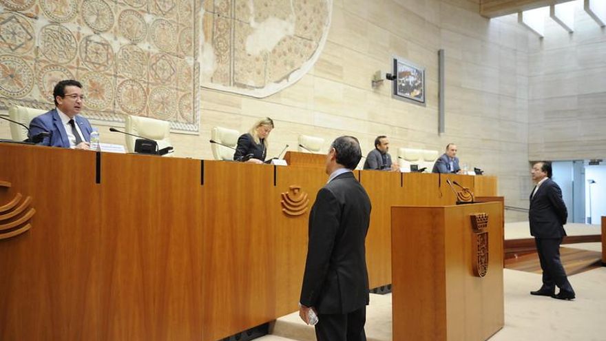 El pleno parlamentario se ha organizado con medidas de prevención, en la imagen Laureano León (PP, de espaldas) y Fernández Vara, hablan con los miembros de la Mesa guardando la distancia de seguridad