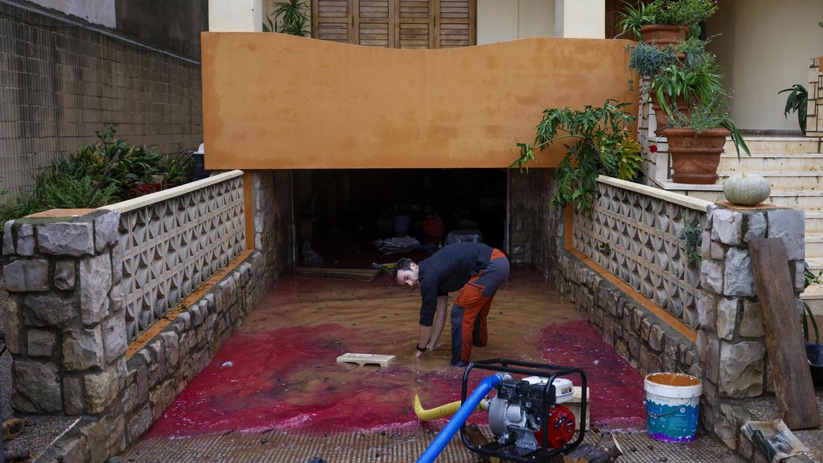 Una persona intenta desaguar su garaje anegado por las lluvias torrenciales que afectan a la Comunitat Valenciana, y especialmente a la provincia de Valencia, en la que se ha establecido el aviso rojo