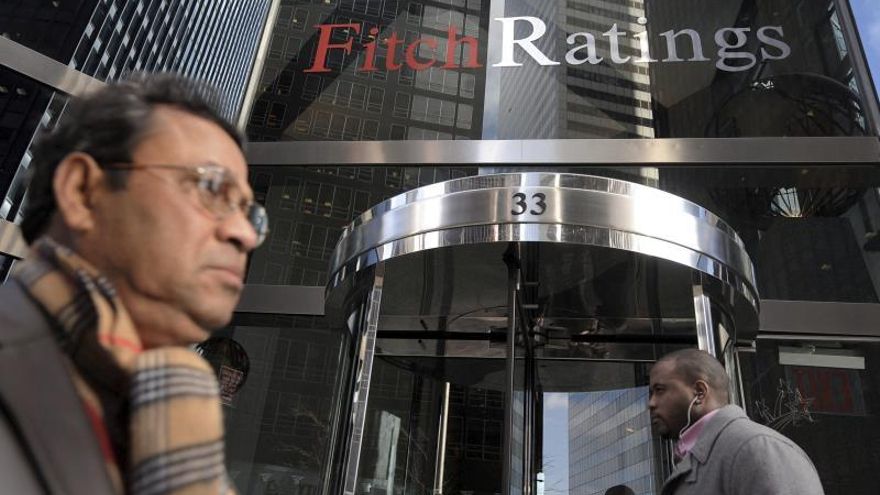 Dos viandantes pasan frente a la entrada de la sede de la agencia de calificación Fitch en Nueva York.