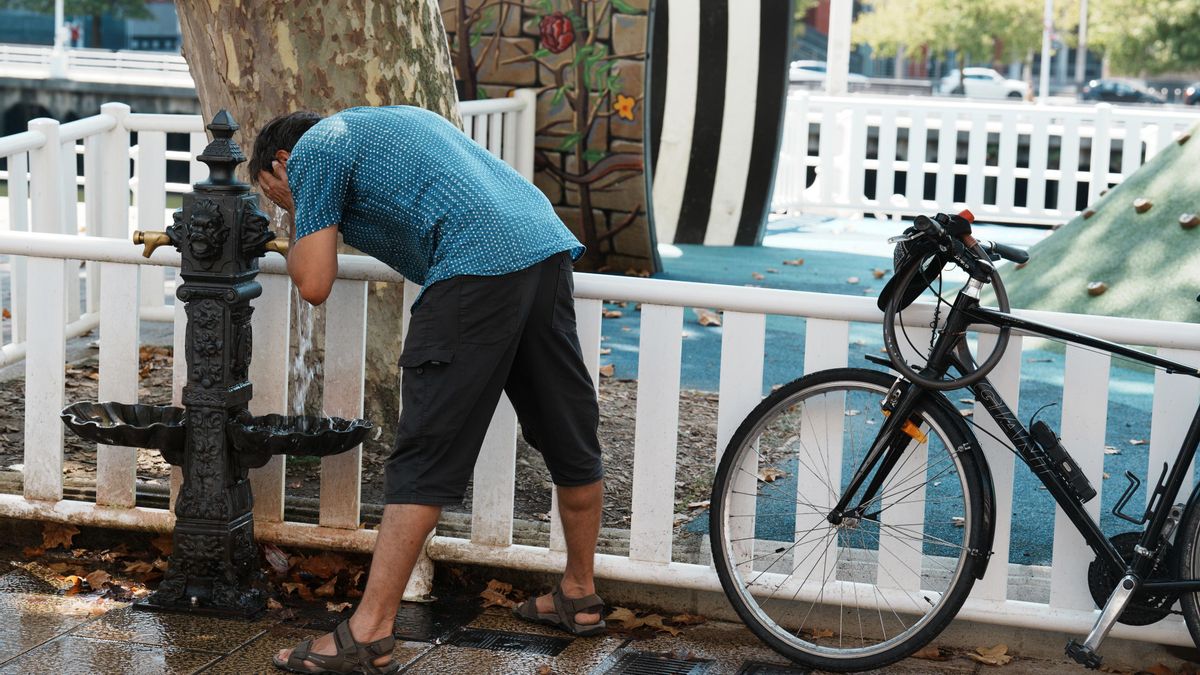 Un hombre se moja la cara con el agua de una fuente durante una ola de calor.